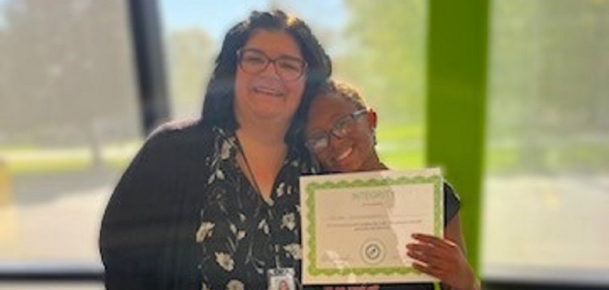 woman wearing glasses and student wearing glasses holding certificate